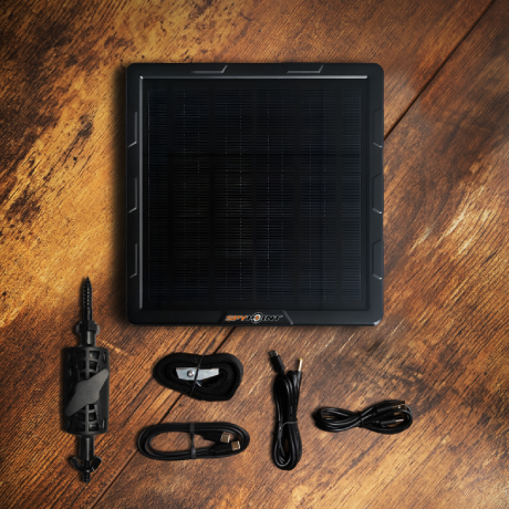 SPYPOINT SPLB-10 panel with full accessory kit displayed on a wooden surface including mount, cable, and fasteners